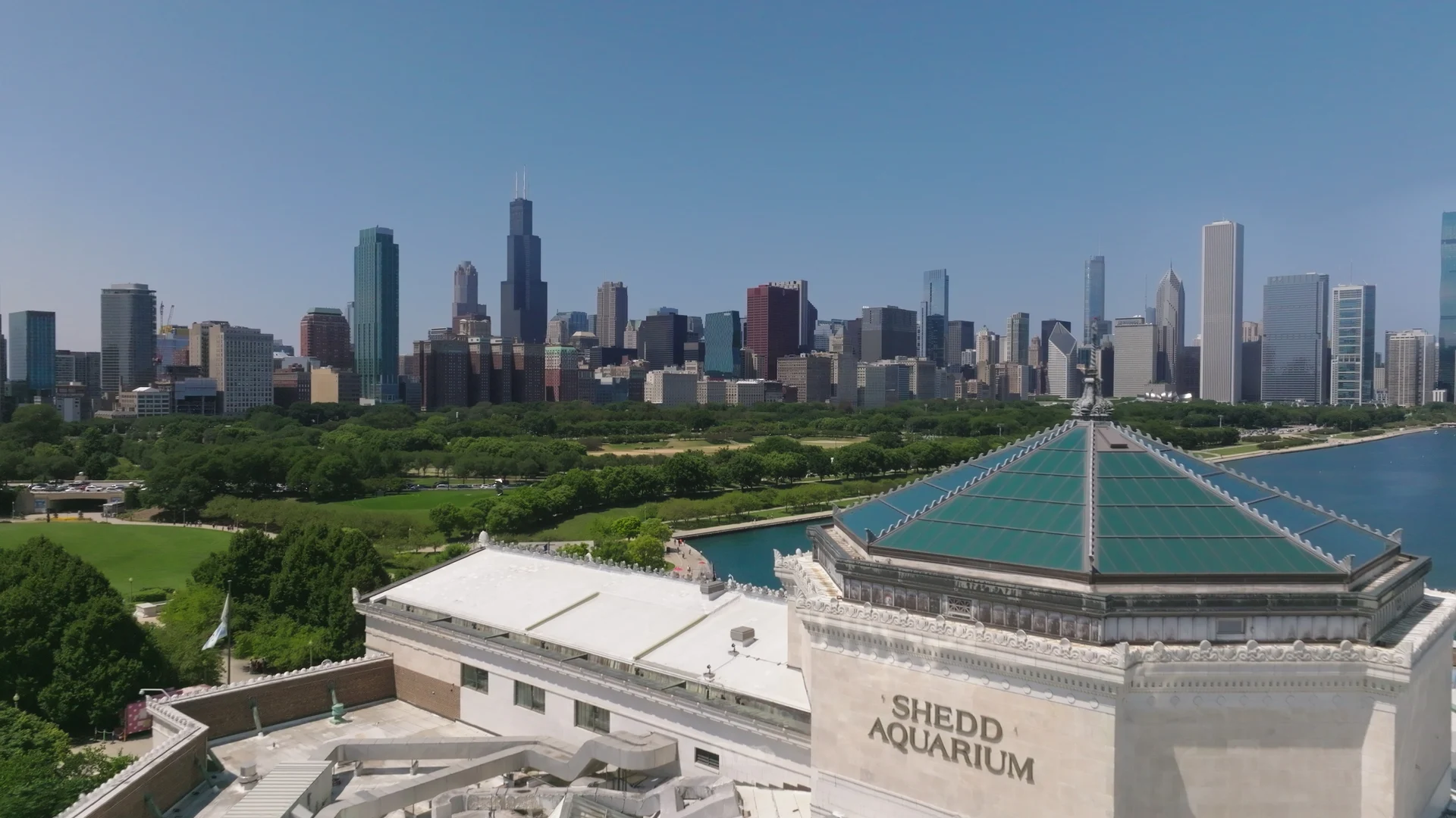 Schriftzug und grünes Dach des Shedd Aquarium mit Chicagos Skyline im Hintergrund
