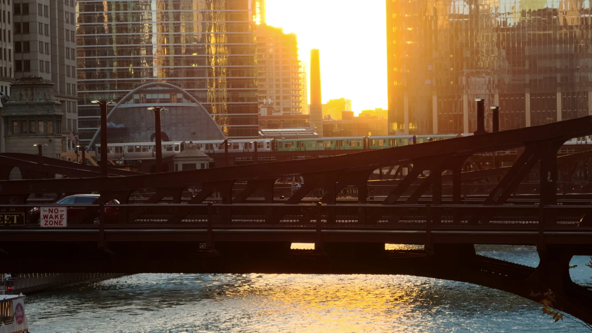 Eine Hochbahn überquert bei Sonnenuntergang eine Stahlbrücke über den Chicago River