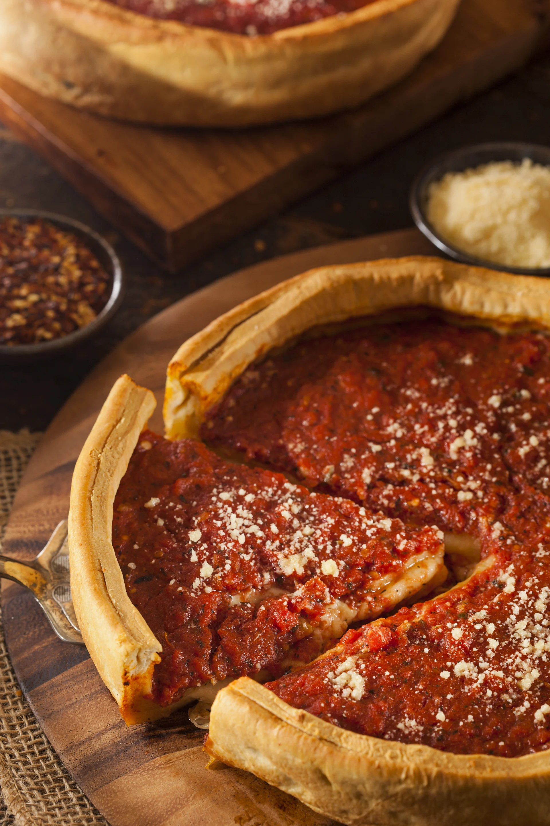 Deep-Dish-Pizza nach Chicagoer Art; ein entnommenes Stück zeigt die dicke Füllung