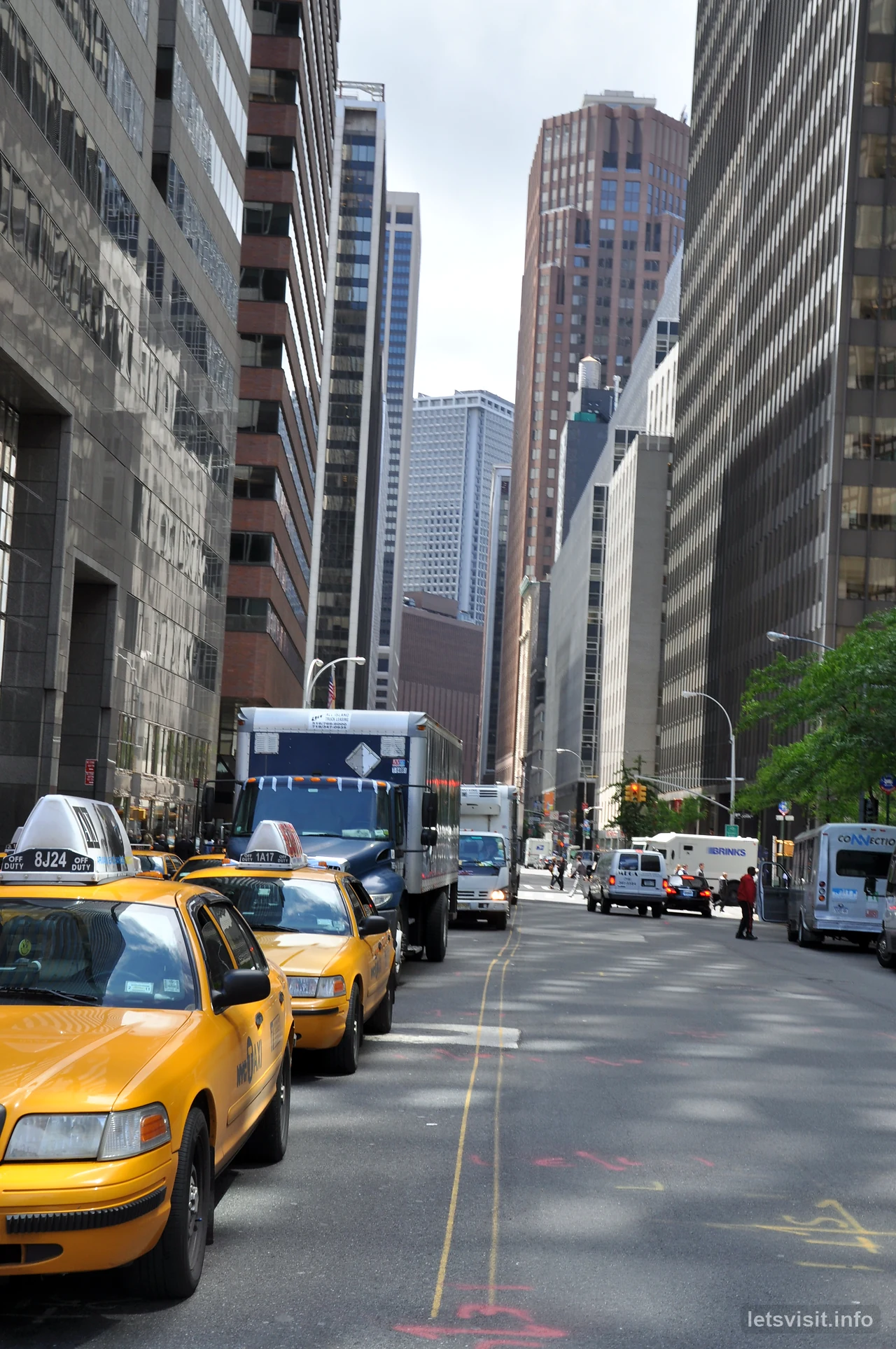 Teksi kuning di jalan sempit antara bangunan tinggi Manhattan
