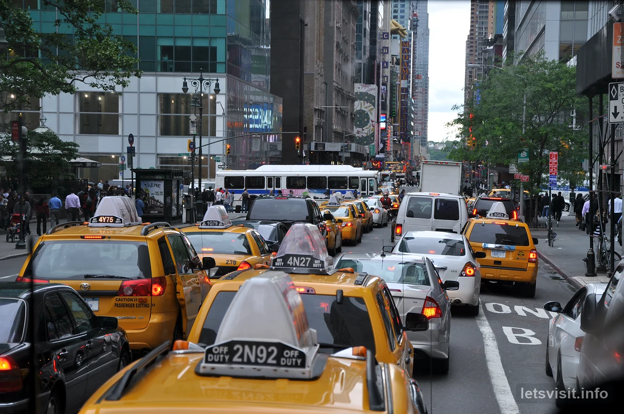 Beberapa teksi kuning dan lalu lintas kota di antara bangunan Manhattan