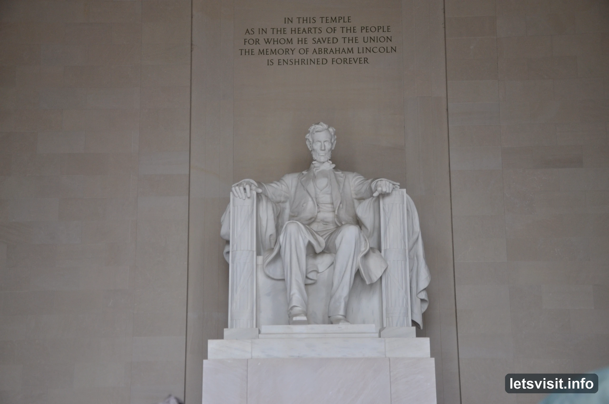 Seated marble statue of Abraham Lincoln beneath the memorial inscription