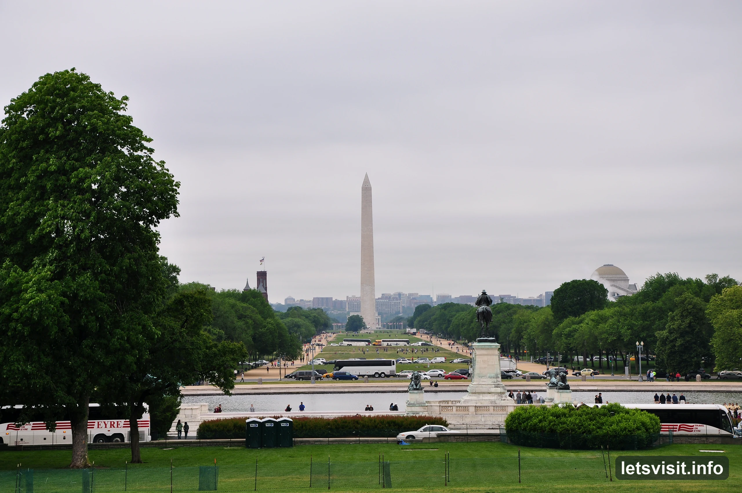 View west across the National Mall toward the Washington Monument, with trees, coaches and lawns