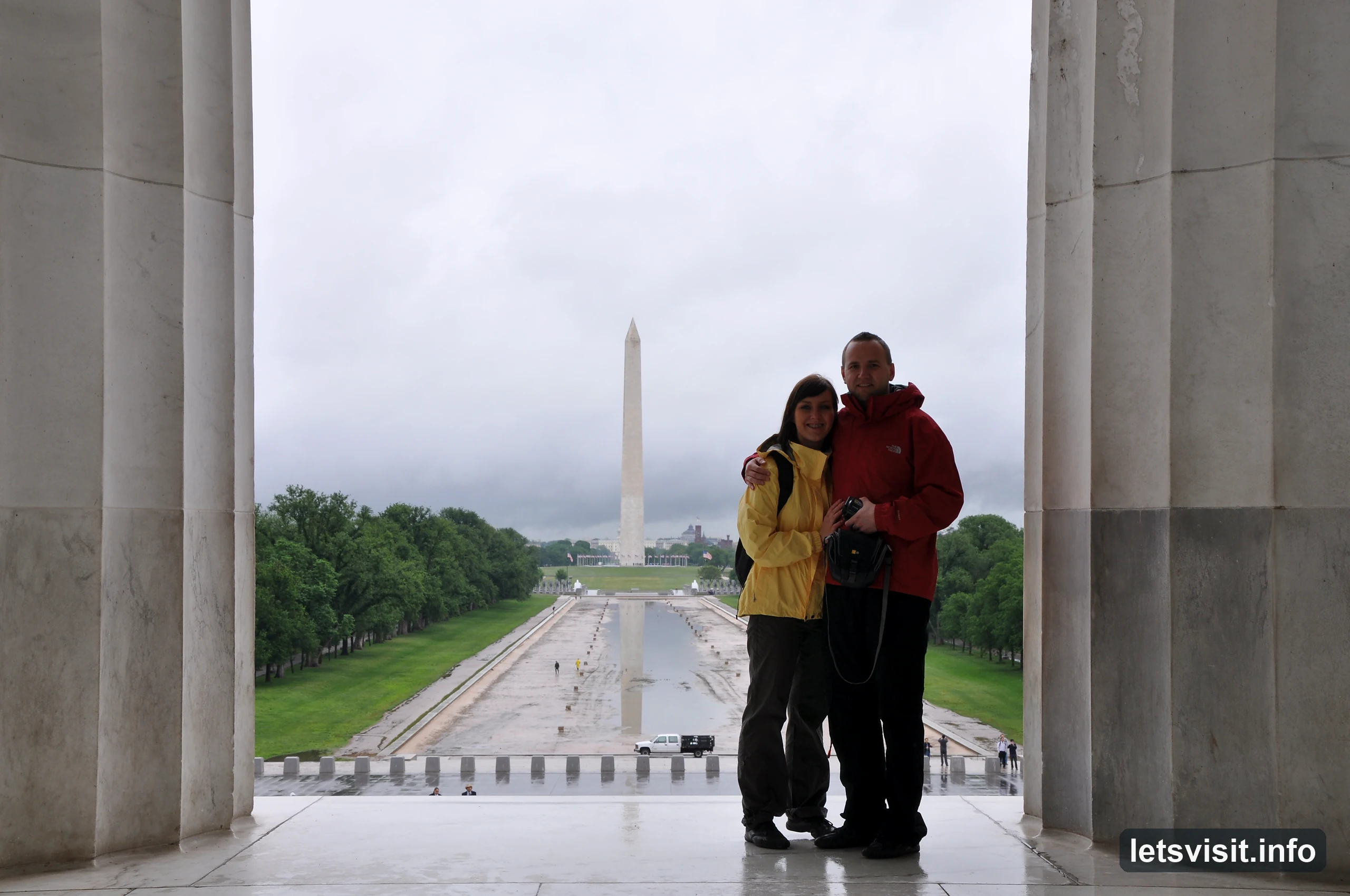 Two travellers between Lincoln Memorial columns with the Washington Monument behind them